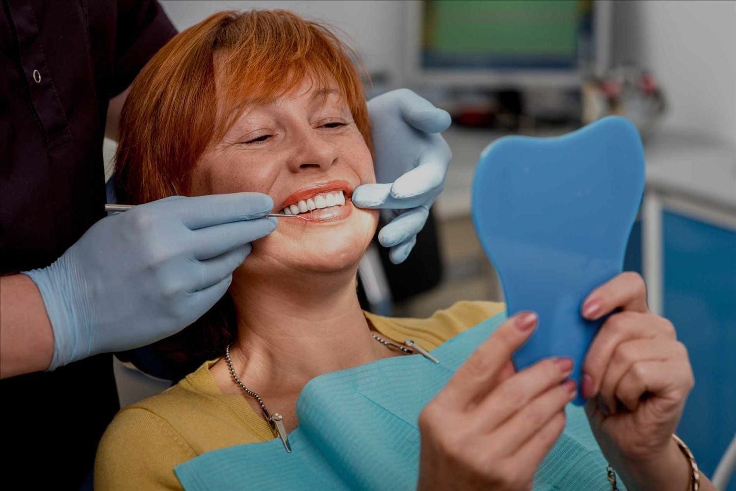 Women Smiling at Mirror While Dentist is Performing Teeth Cleaning