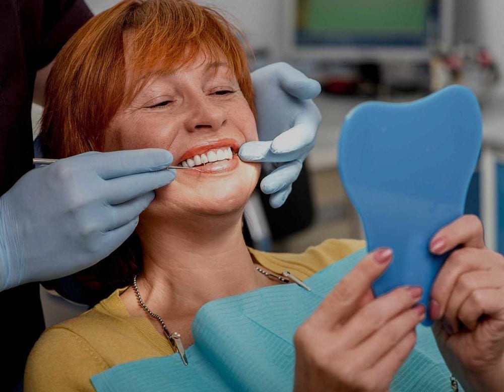 Women Smiling at Mirror While Dentist is Performing Teeth Cleaning